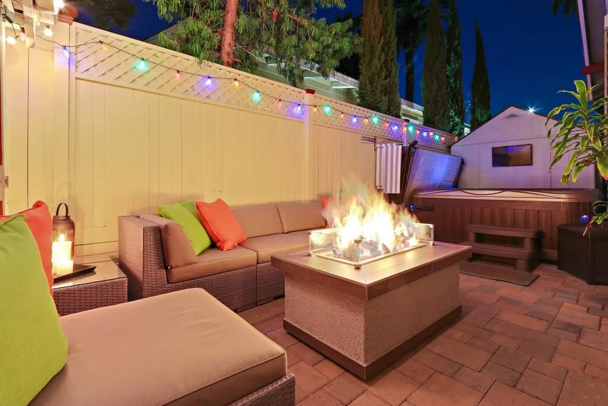 Fire-pit lounge and hot tub at night under string lights